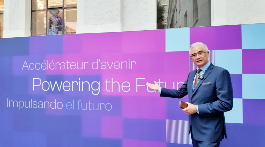 Dr. John K. Hsiang poses beside the Powering the Future backdrop at the WTO Public Forum 2026 in Geneva
