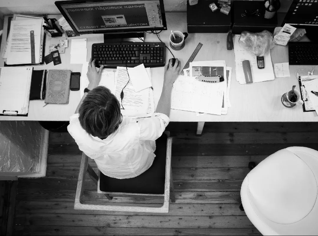 A young professional working late at a cluttered desk, illustrating overwork and chronic stress as risk factors for heart attack